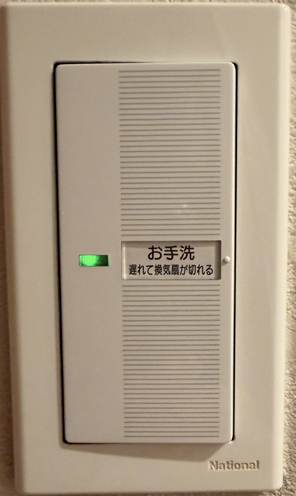 交換後のトイレのスイッチ。お手洗 遅れて換気扇が切れるの表示と緑のランプ